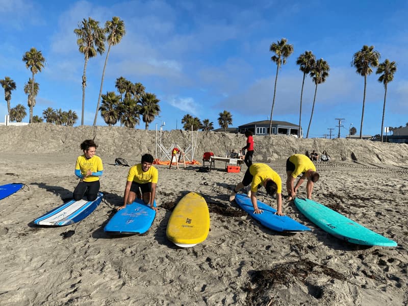 Team members on the beach with surfboards for a San Diego off-site event.